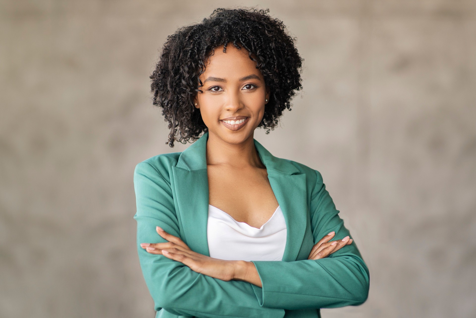 Happy Black Businesswoman Crossing Hands Over Gray Office Wall