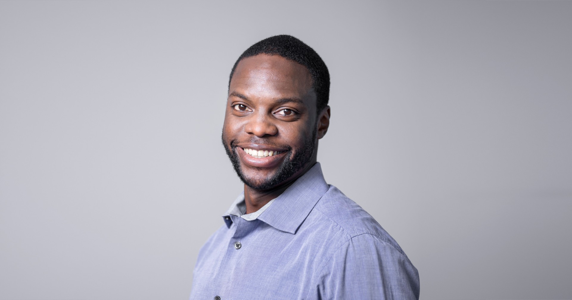 Young businessman smiling over gray background