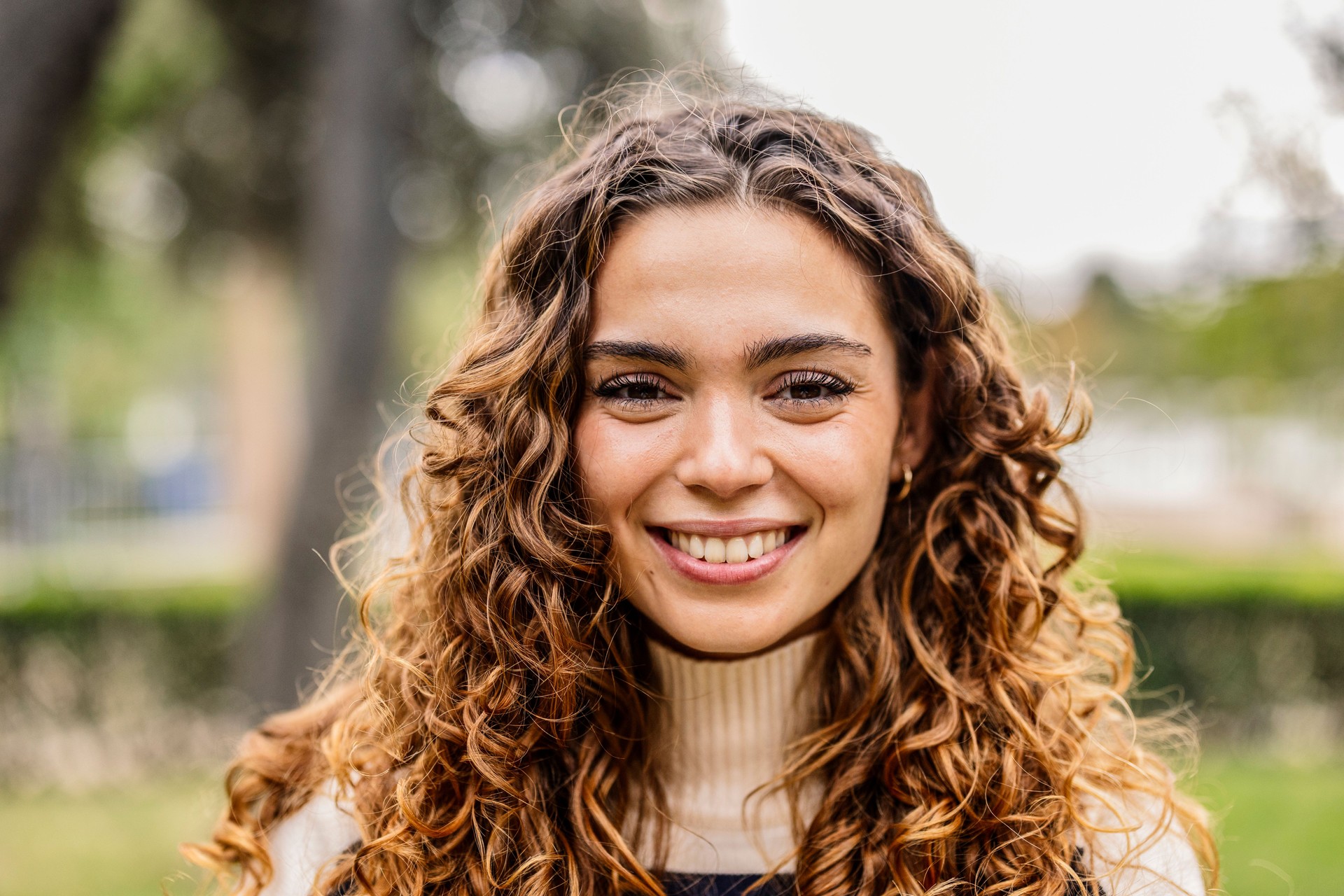 Radiant Young Woman with Curly Brown Hair Outdoors